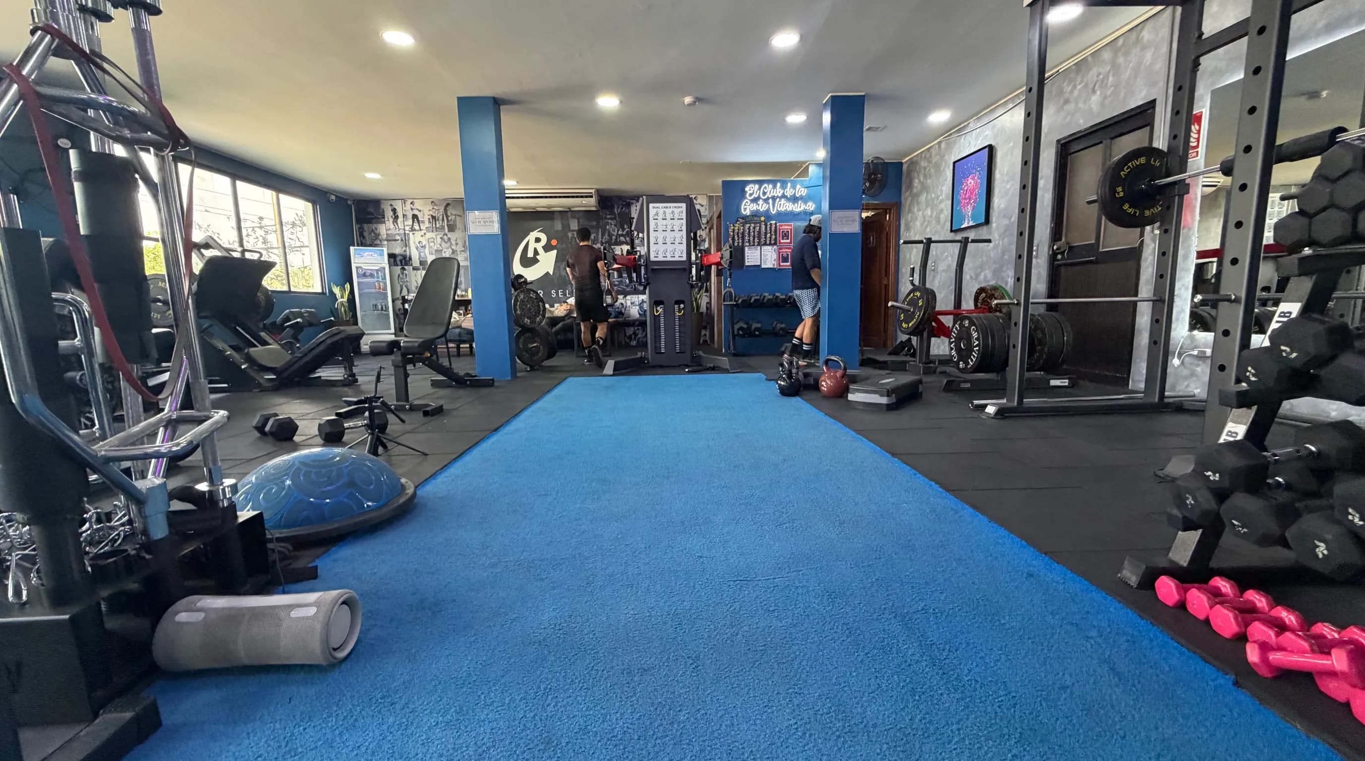 Piso de entrenamiento de la sede Entreríos: pasillo de grama azul entre racks, mancuernas y máquinas
